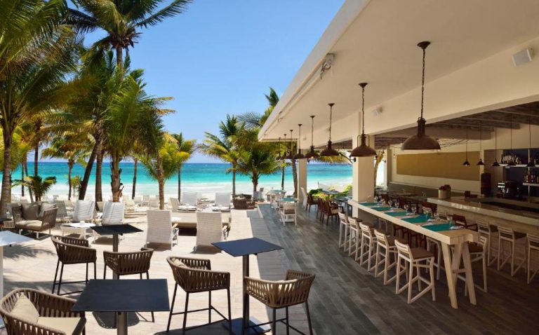 Restaurante bar frente al mar con terraza y palmeras en Catalonia Royal Tulum Beach & Spa Resort