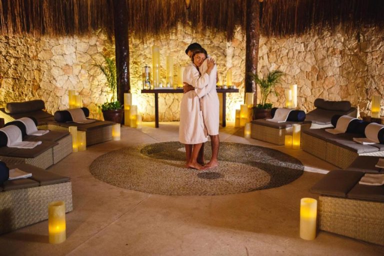 Pareja en albornoces abrazándose en el spa romántico del Catalonia Royal Tulum Beach & Spa Resort