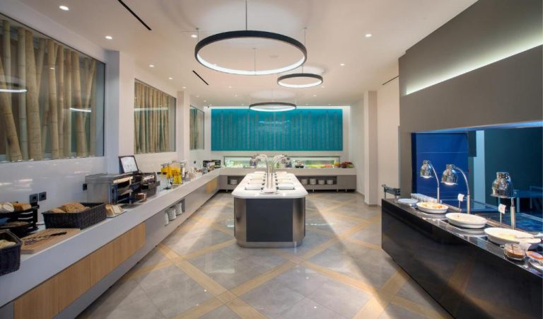 Zona de buffet desayuno moderno con isla central e iluminación circular en Blue Lagoon City Hotel