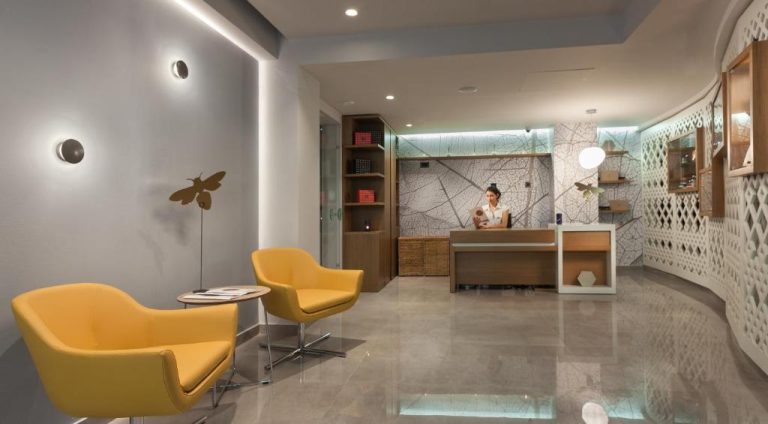 Recepción moderna del Blue Lagoon City Hotel con sillas amarillas y mostrador de atención al cliente