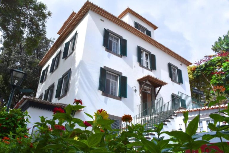 Fachada exterior blanca con ventanas verdes y jardín de la Quinta da Penha de Franca en Madeira