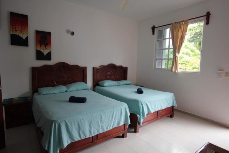 Habitación twin con dos camas de madera tallada y ropa de cama azul en Villas Roseliz