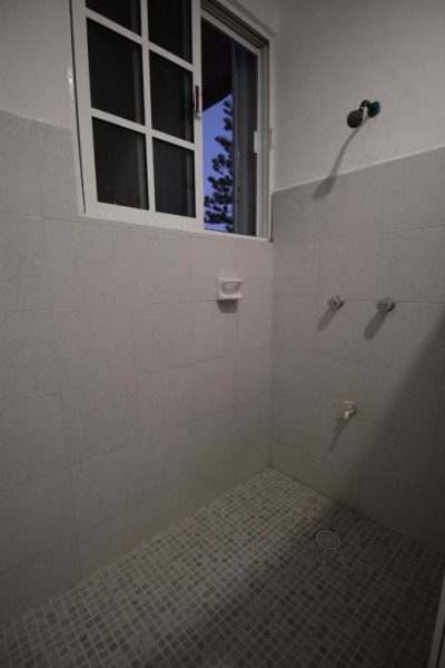 Baño con ducha de azulejos blancos y ventana exterior en Villas Roseliz