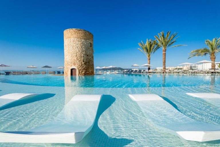 Piscina infinita con torre medieval histórica y palmeras del Hotel Torre del Mar en Ibiza