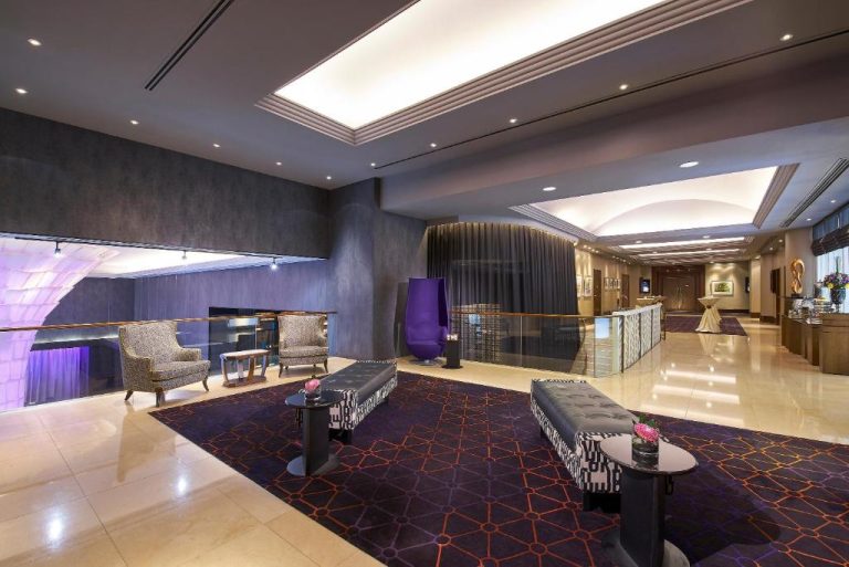 Elegante lobby del Rendezvous Hotel Singapore con sofás modernos, alfombra morada y zona de recepción iluminada