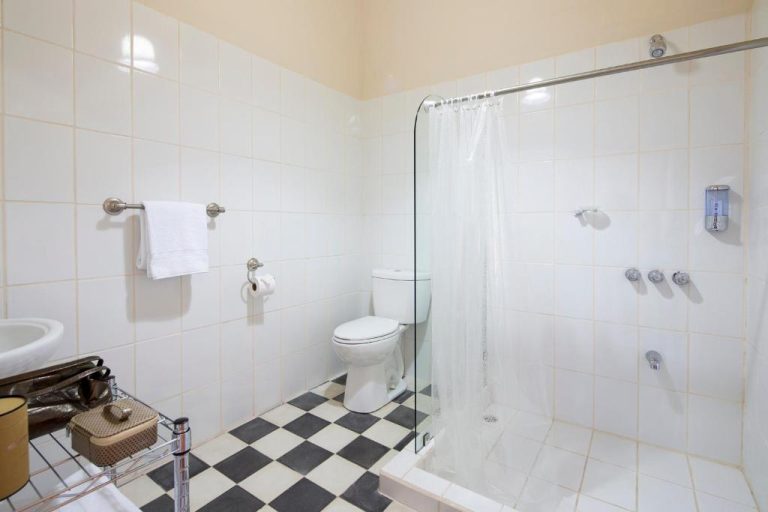 Baño completo con ducha de cristal, suelo a cuadros y sanitarios blancos en Villa San Ignacio
