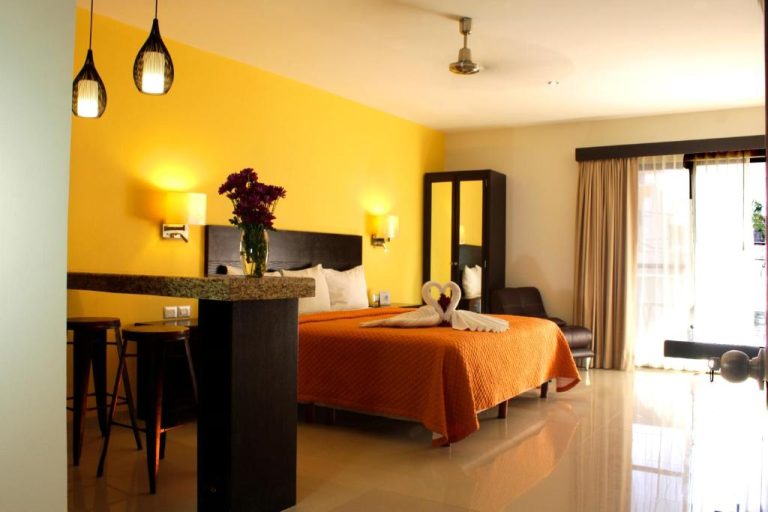 Habitación doble con cama king size y decoración en amarillo del Hotel Nautilus con balcón