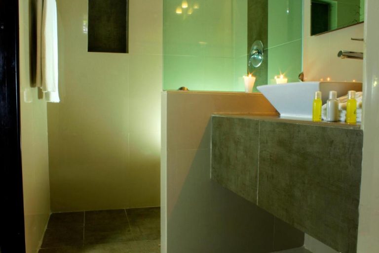 Baño moderno con lavabo suspendido, velas decorativas y amenities en Hotel Nautilus