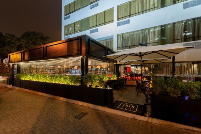 Terraza exterior nocturna con zona de bar y jardines iluminados del Roosevelt Hotel & Suites