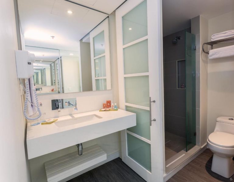 Baño moderno con ducha de cristal y lavabo empotrado en el Hotel GHL Corales de Indias