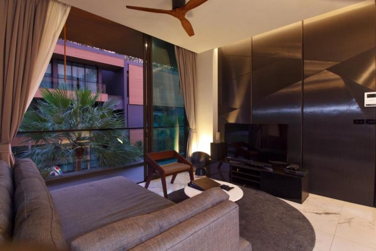 Salón moderno con sofá, televisor y terraza con vistas a jardín tropical en Glam Habitat SHA Extra Plus