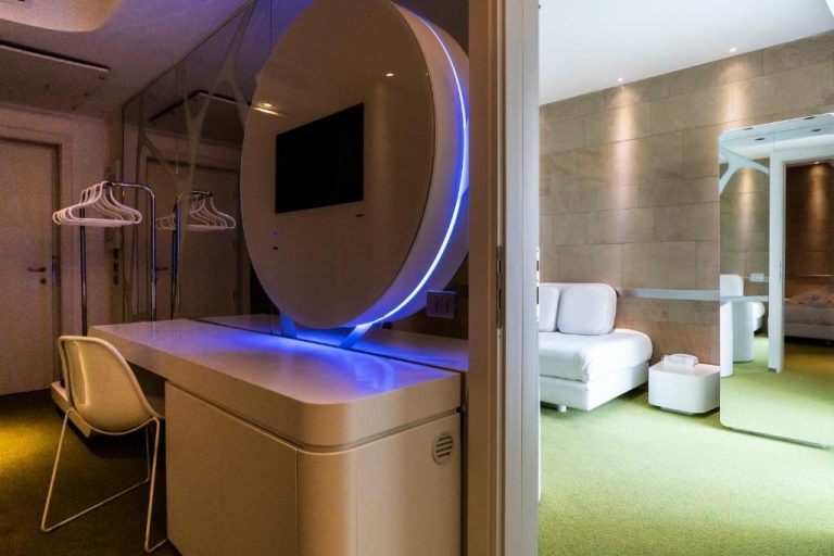 Habitación futurista con espejo LED azul y televisión integrada en A Point Arezzo Park Hotel