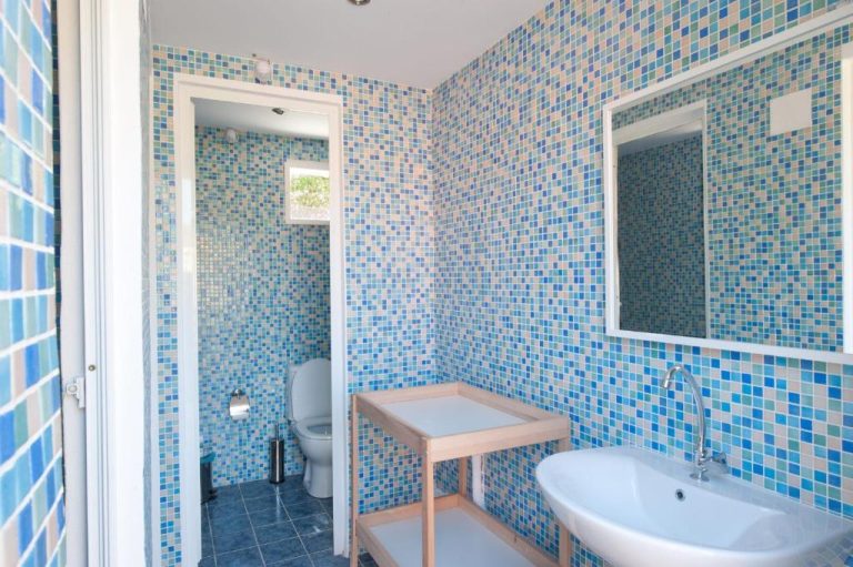 Baño con azulejos de mosaico azul, lavabo y aseo en Marina Apartments Agios Gordios Corfú