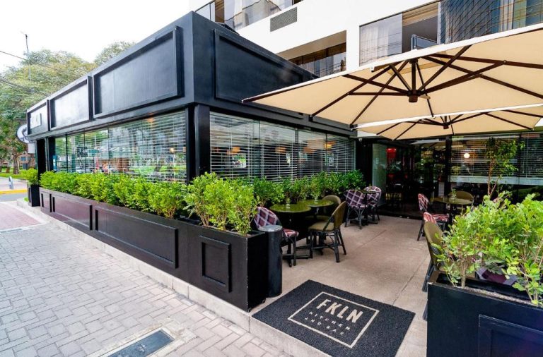 Terraza exterior con mesas y sombrillas del restaurante FKLN Kitchen and Bar en Roosevelt Hotel & Suites