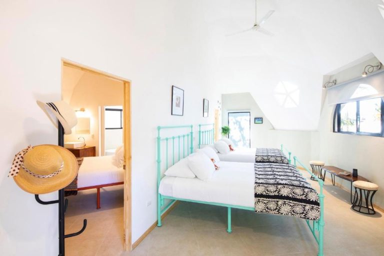 Habitación doble con camas de hierro turquesa y techo alto en Villa San Ignacio