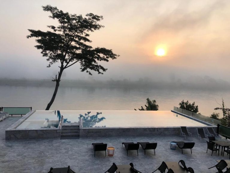 Piscina infinita con vista al río al amanecer en Chiangkhong Teak Garden Riverfront Onsen Hotel