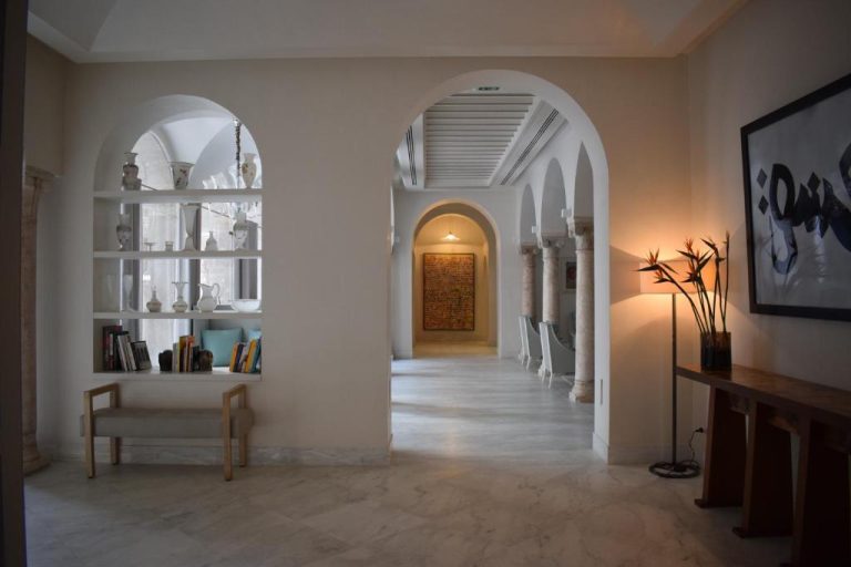 Elegante corredor con arcos blancos y columnas del Dar El Jeld Hotel and Spa en Túnez