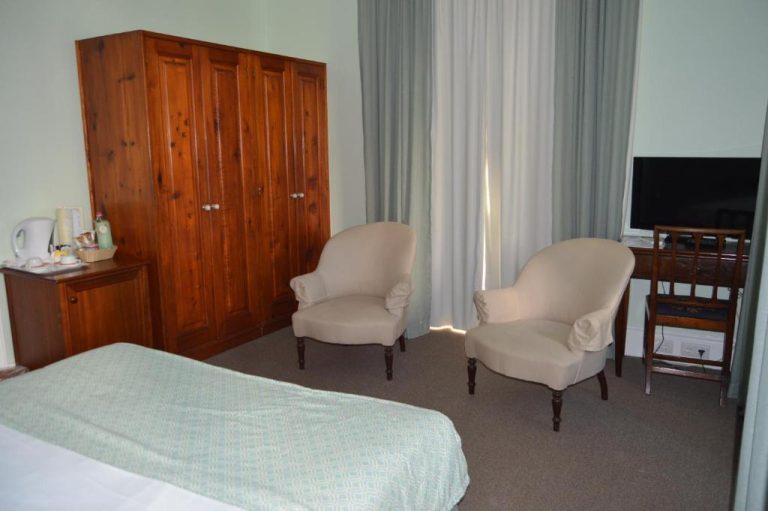 Habitación doble con armario de madera, sillones y televisión en Quinta da Penha de Franca