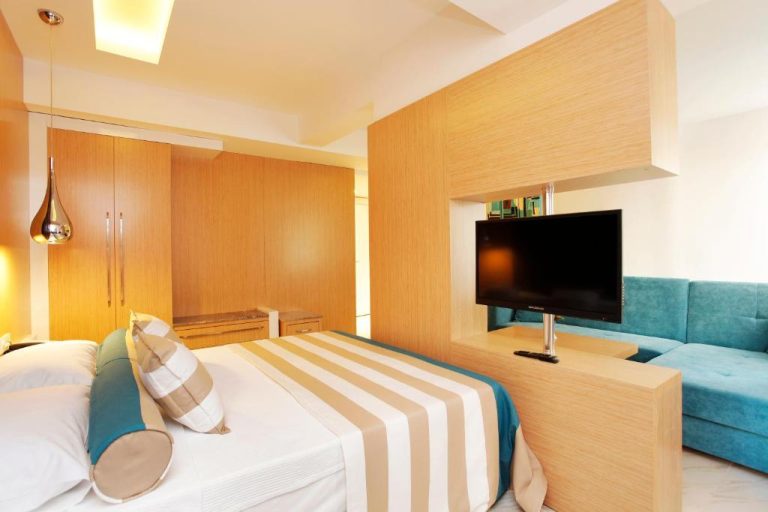 Suite moderna con cama doble, sofá azul y televisión en el Kleopatra Suit Hotel
