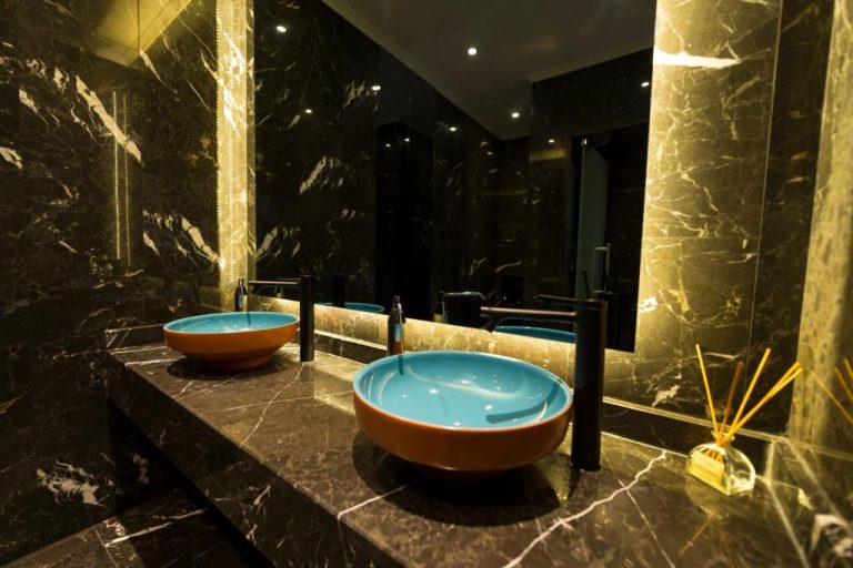 Baño de lujo con lavabos turquesa sobre encimera de mármol negro en Kleopatra Suit Hotel