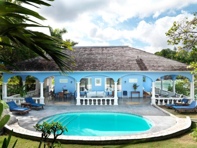 Piscina exterior con terraza y villa de color azul en Jamaica Inn con vistas al mar Caribe