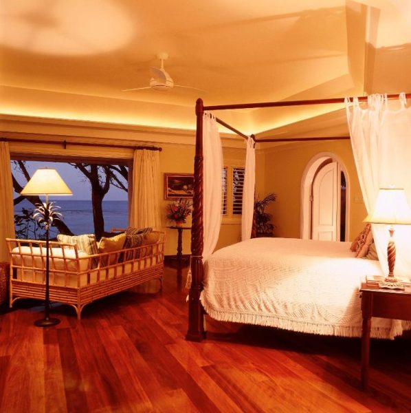 Suite de lujo con cama de dosel y vistas al mar al atardecer en Jamaica Inn