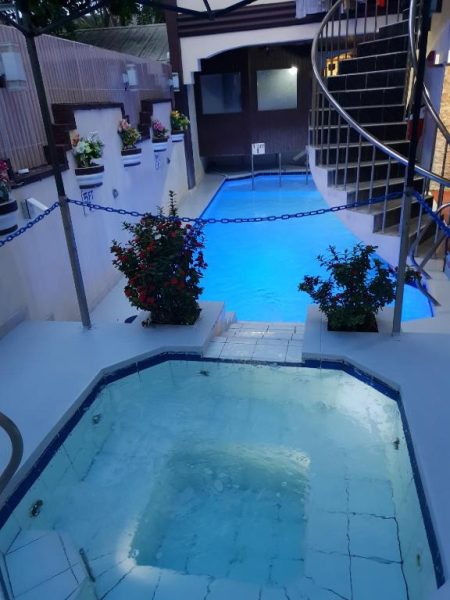 Piscina exterior iluminada con jacuzzi y plantas decorativas en Cool Martin Family Hotel and Resort