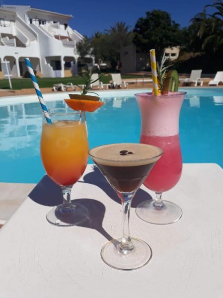 Tres cócteles tropicales junto a la piscina exterior del Hotel Vilamar en un día soleado