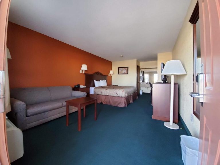 Suite amplia con sofá, cama doble y alfombra azul en el Cuba Inn Hotel