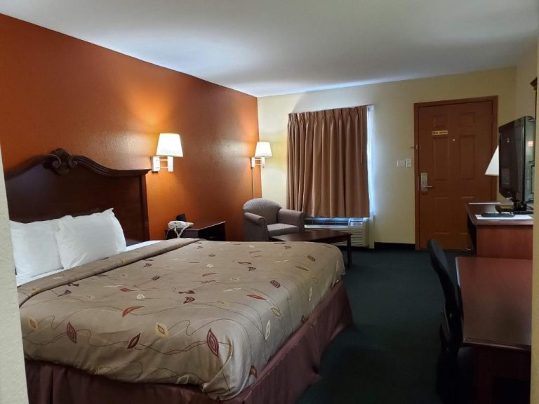 Habitación con cama doble, escritorio y televisión en el Cuba Inn, decoración en tonos tierra