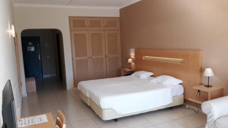 Habitación doble con cama grande, armario de madera y mesitas con lámpara en Hotel Vilamar