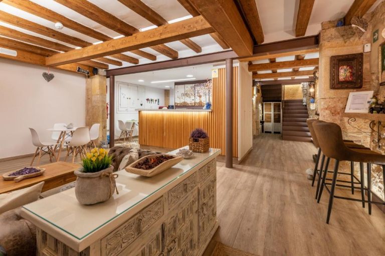 Recepción y zona común del Hostal 977 con vigas de madera y decoración rústica en piedra