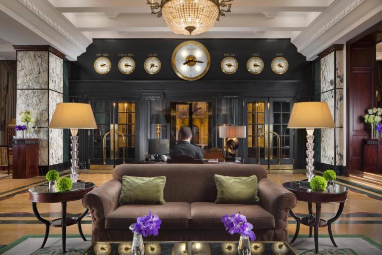 Elegante lobby del Esplanade Zagreb Hotel con relojes mundiales, sofá clásico y lámparas de cristal