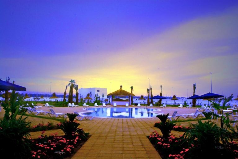 Piscina exterior con tumbonas y gazebo al atardecer en Relax Hotel Airport Nouasseur