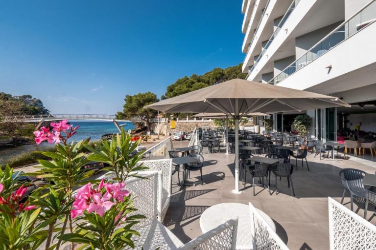Terraza exterior con mesas y sombrillas del ARTIEM Audax Adults Only con vistas al mar en Menorca