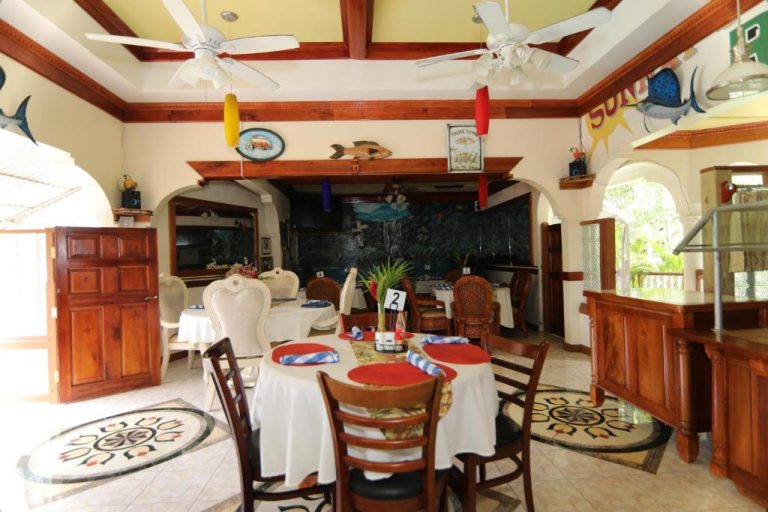 Restaurante del Rayon Hotel con decoración tropical, mesas vestidas y murales de peces en las paredes