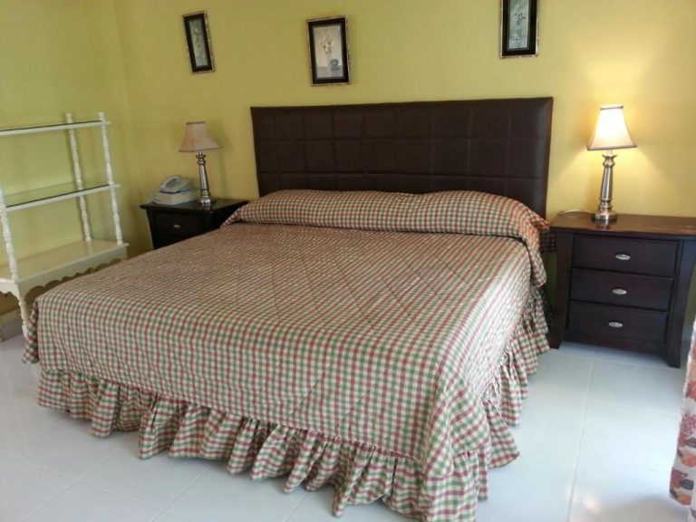 Habitación doble con cama king size y cabecero de cuero marrón en Negril Beach Club Condos