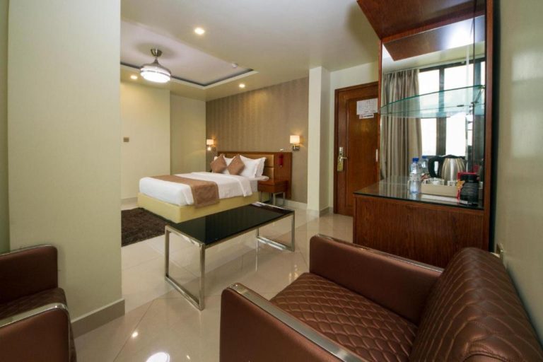 Suite con salón, sofás de cuero y cama doble en el Hotel Unima Grand