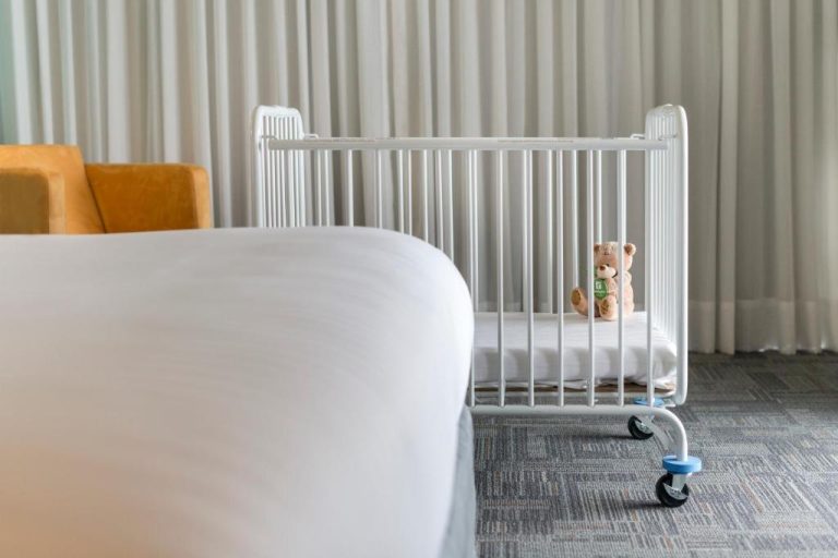 Cuna de bebé con osito de peluche junto a cama doble en Holiday Inn Lima Airport by IHG