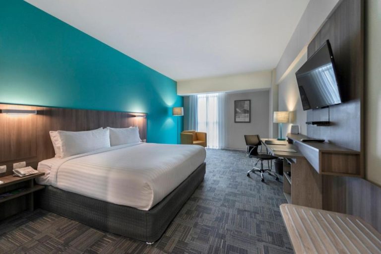 Habitación king con pared turquesa, escritorio de trabajo y TV en Holiday Inn Lima Airport