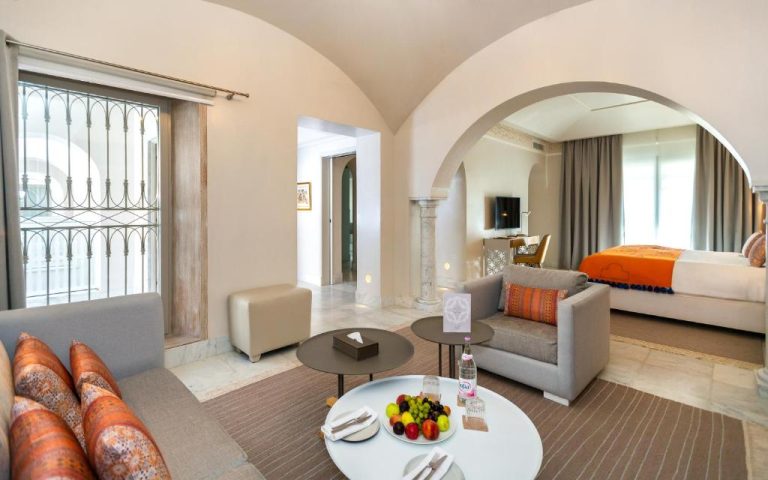 Suite de lujo con arco decorativo y salón elegante en Dar El Jeld Hotel and Spa en Túnez