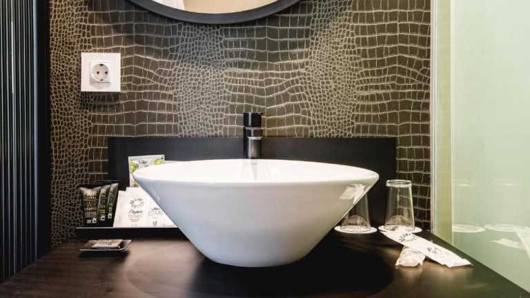Elegante baño con lavabo de porcelana y pared texturizada en Be Live Adults Only La Cala Boutique Hotel