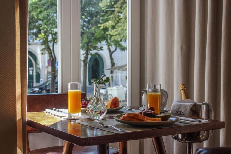 Mesa de desayuno con frutas frescas y zumo de naranja en Lisboa Carmo Hotel con vistas a la calle