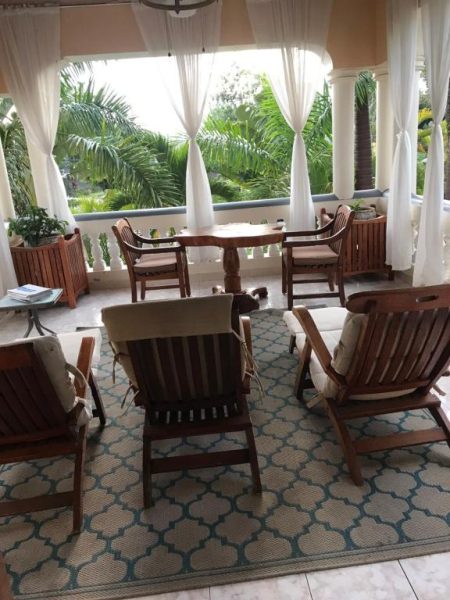 Terraza exterior con sillones de madera y vistas a jardines tropicales en Rayon Hotel