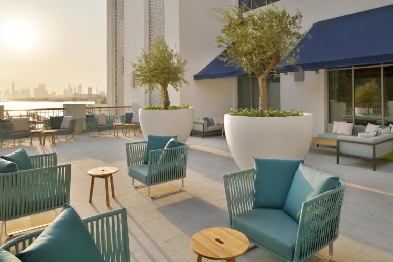 Terraza lounge exterior con sillones turquesa y vistas al skyline en el hotel Vida Creek Harbour Dubai
