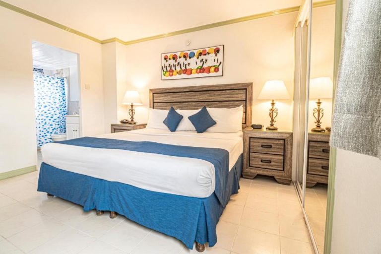 Habitación con cama doble y decoración azul en Worthing Court Apartment Hotel Barbados