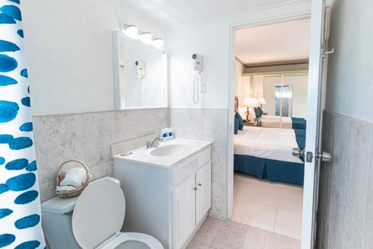 Baño completo con lavabo y ducha del Worthing Court Apartment Hotel con vista a habitación doble