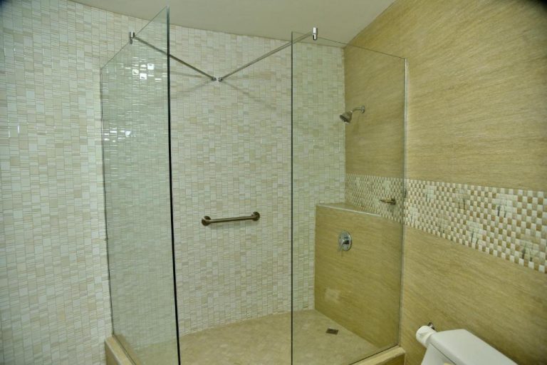 Baño con ducha de cristal y azulejos de mosaico beige en el Hotel Grand A View