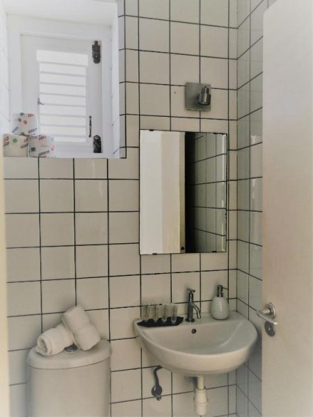 Baño con azulejos blancos, lavabo y espejo del Landhuis Klein Santa Martha Boutique Hotel