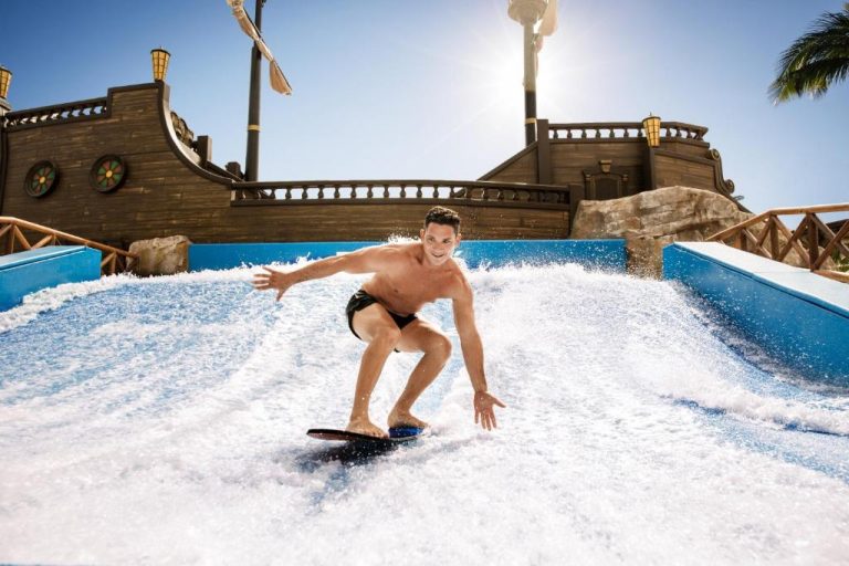 Hombre surfeando en el simulador de olas FlowRider del hotel Barceló Maya Tropical All Inclusive México